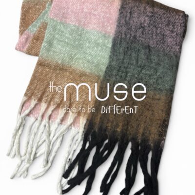 An oversized blanket scarf featuring large color blocks of blush pink, mint green, tan, and charcoal grey, finished with thick, chunky tassels in cream and black.